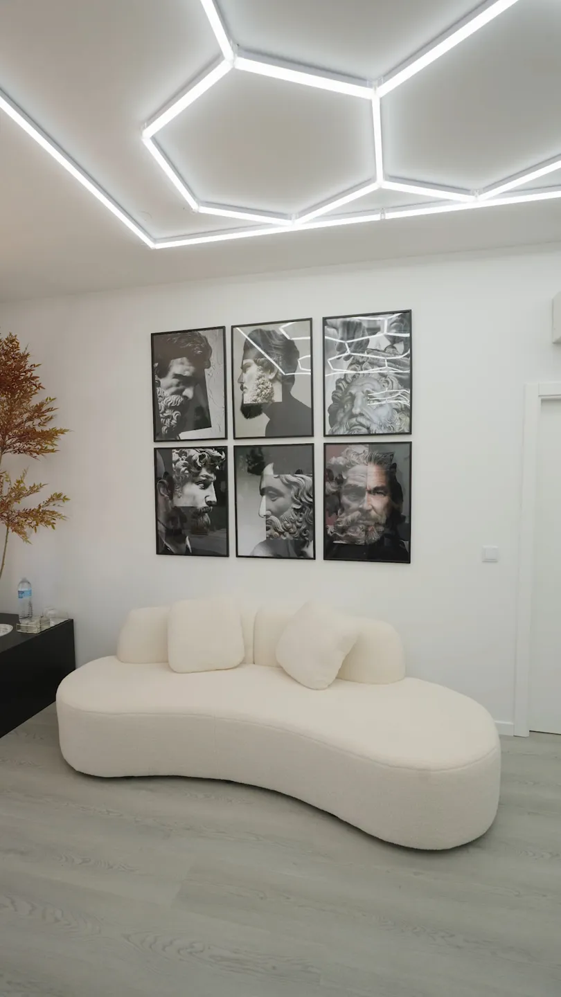 A sala de espera, com a galeria de retratos clássicos sobre o sofá curvo em bouclé