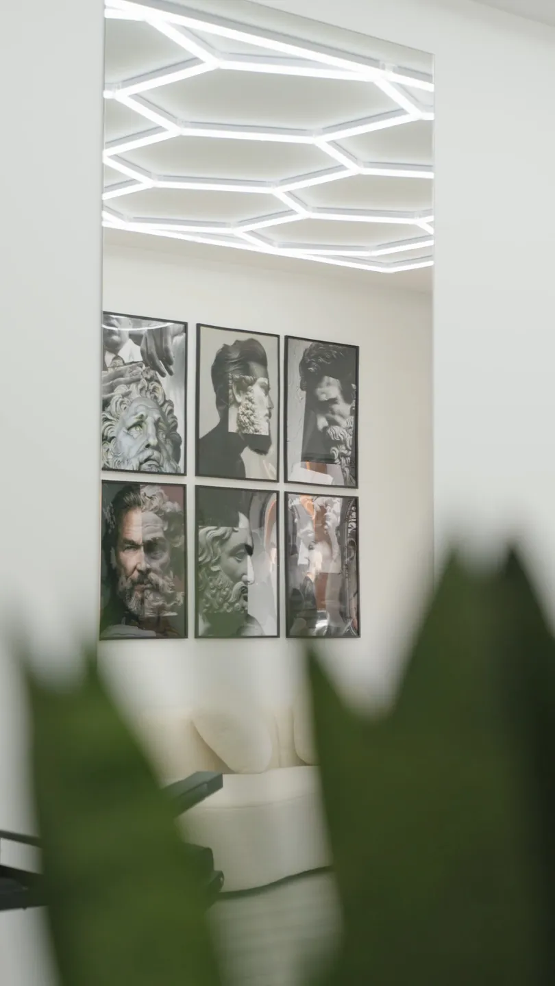 A galeria de bustos greco-romanos e o teto em favo de mel, vistos por entre a folhagem